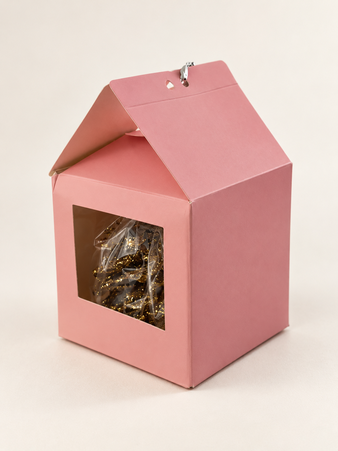 Enhanced photo of the CrunchCone prototype: dusty-pink handled box with a clear window, inner bag and gold-speckled pinecone